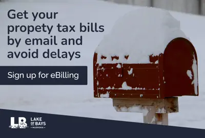 A red mailbox covered in snow sits on a wooden post in a snowy landscape. The mailbox door is slightly open. Text on the image reads: “Get your property tax bills by email and avoid delays. Sign up for eBilling.