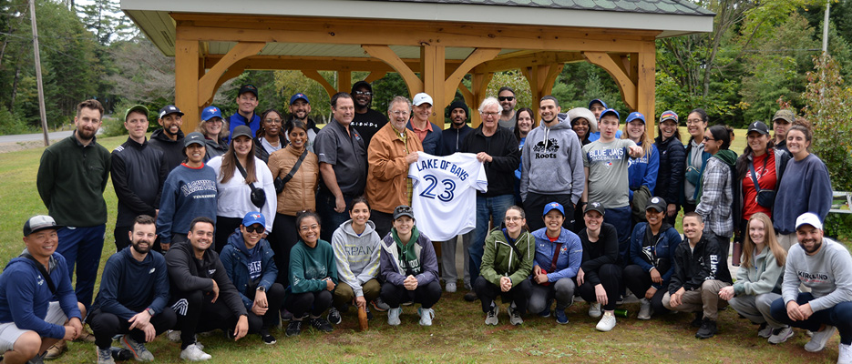 Group photo of the Blue Jays Foundation, Parks Department Superintendent Scott MacKinnon, Township Mayor Terry Glover, and Lake of Bays Township trail maintenance volunteer Doug Ward holding a gifted Blue Jays jersey in the middle.