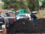 People gathering compost from large pile
