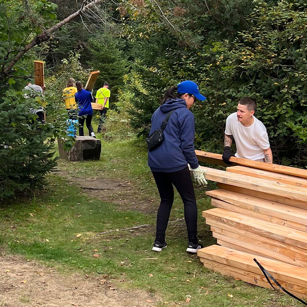 Jays Care Foundation volunteers carrying lumber for the Echo Valley trail system