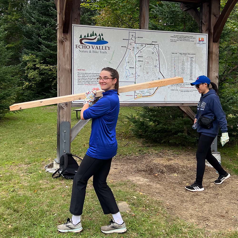 Jays Care Foundation volunteer carrying lumber for the Echo Valley trail system