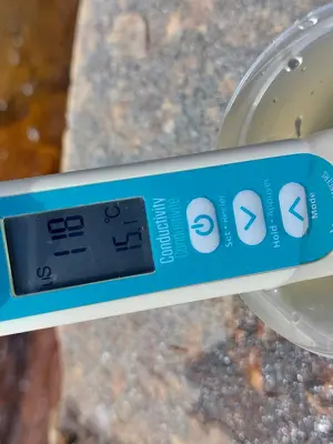 A handheld conductivity meter in a water sample.