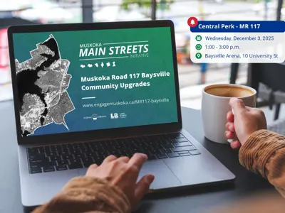Person with coffee viewing MR117 Baysville project webpage on laptop, event details shown beside screen.