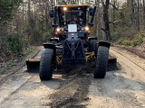 a large grader driving down a dirt road